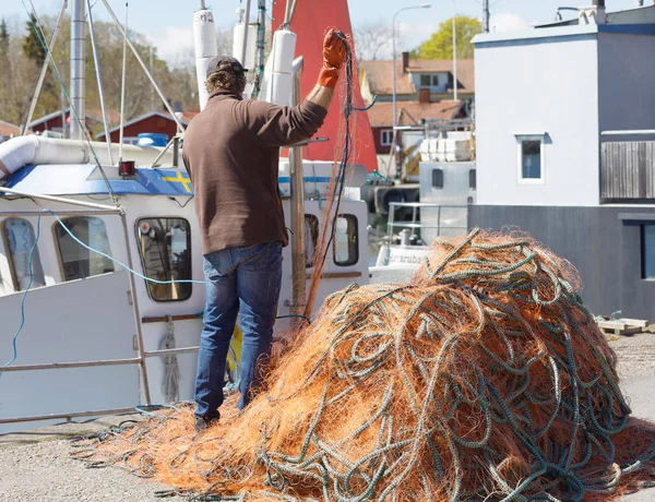 Pescador fijando sus redes de pesca en frente del barco de pesca — Foto de Stock