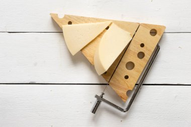 Peynir peynir kesici karşı Beyaz ahşap bir masa üzerinde