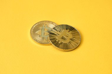 Sarı bir arka plan üzerinde iki adet altın sikke bitcoin