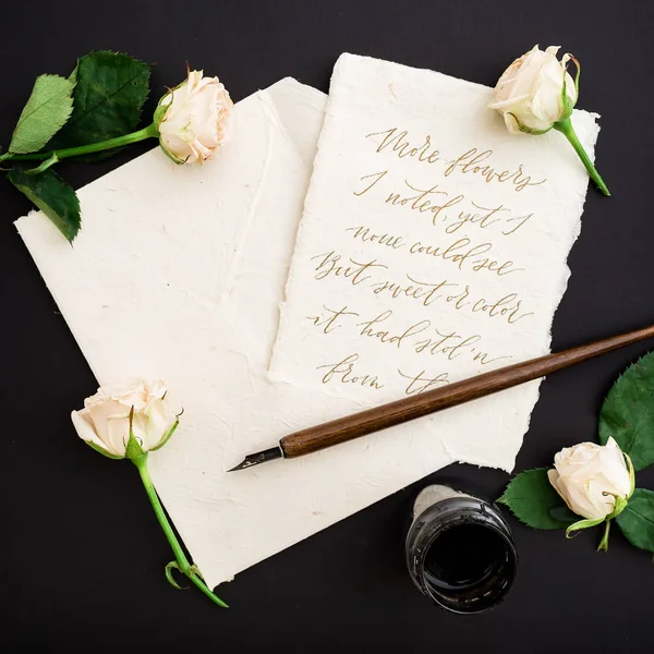 Vintage sheet of paper with dip pen and inkstand on black background with tender roses