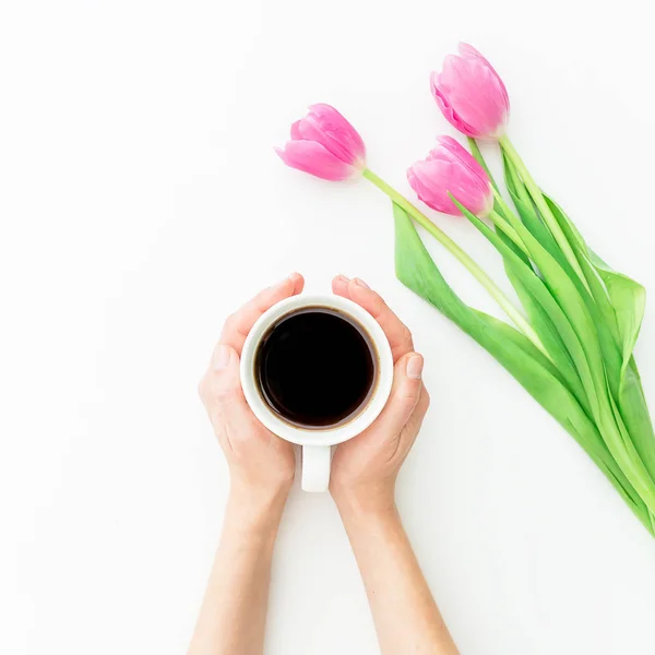 Blommor och kaffekopp i händer — Stockfoto