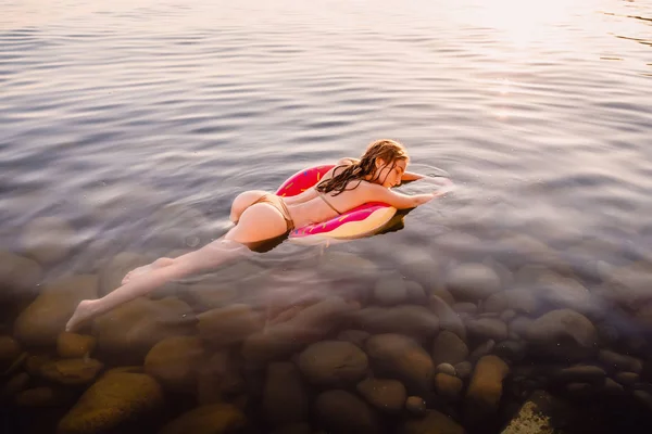 Frau schwimmt auf dem aufblasbaren Donut — Stockfoto