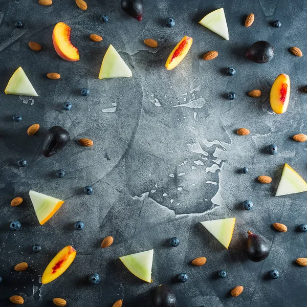 Şeftali, kavun, yaban mersini ve badem karanlık tablo çerçeve. Meyve kavramı. Düz yatıyordu, en iyi görünümü