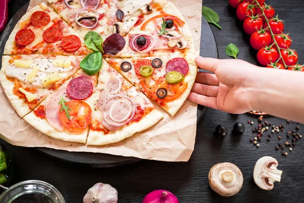 Человеческая рука берет кусок пиццы — стоковое фото