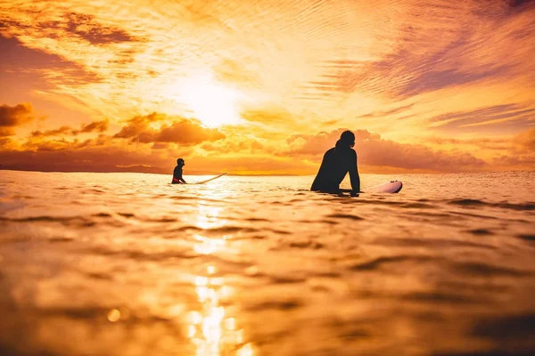 Surfers in ocean at sunset or sunrise. Couple of surfer and ocean — Stock Photo, Image