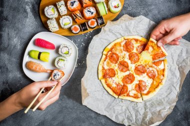 Lezzetli Pizza salam ile dizi suşi rulo ve yemek ellerini almak. Koyu arka plan. Düz yatıyordu, en iyi görünümü.