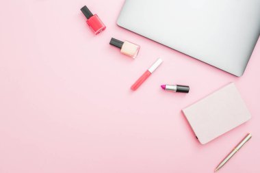 Dizüstü bilgisayar, dizüstü bilgisayar ve pembe bir arka plan üzerinde kozmetik ile ev çalışma masası. Üstten Görünüm. Düz yatıyordu yaşam tarzı kavramı.