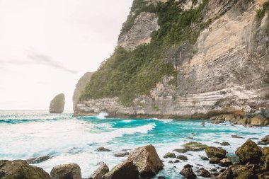Tropikal mavi okyanus dalgaları ve Bali kayalık uçurum. Tropik cennet yerde