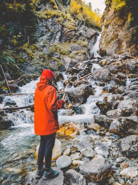 Kayanın üzerinde duran ve üzerinde şelale arayan kadın 