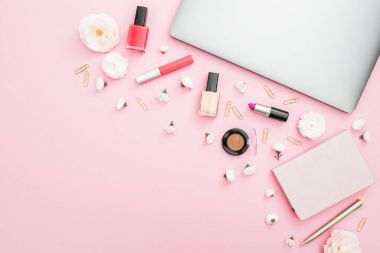 Dizüstü bilgisayar, dizüstü bilgisayar ve pembe bir arka plan üzerinde kozmetik ile ev çalışma masası. Üstten Görünüm. Düz yatıyordu yaşam tarzı kavramı. 