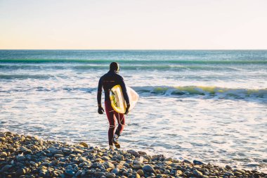 Sörfçü gün batımında. Mayoyla sörf kış