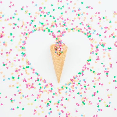 Beyaz arka plan üzerinde renkli şeker konfeti ve gözleme koni kalp sembolü yaptı. Düz yatıyordu