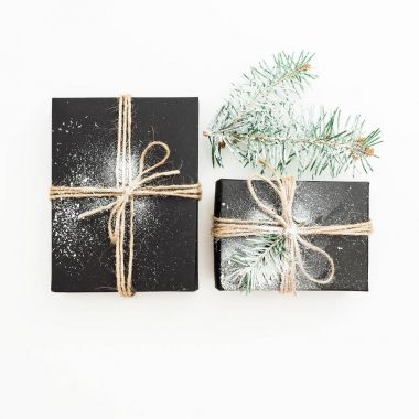 Şık siyah hediye kutuları, çam dalları ve çam kozalakları beyaz arka plan üzerinde Noel çerçeve yaptı. Yeni yıl kavramı. Düz yatıyordu. Üstten Görünüm