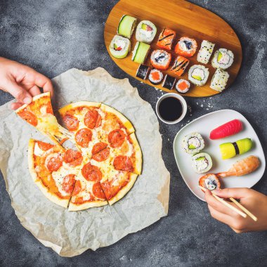 Lezzetli Pizza salam ile dizi suşi rulo ve yemek ellerini almak. Koyu arka plan. Düz yatıyordu, en iyi görünümü.