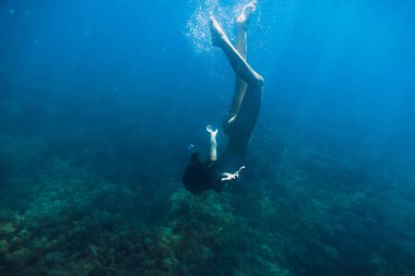 Su altında mavi okyanusta yüzmeye çıplak genç kadın