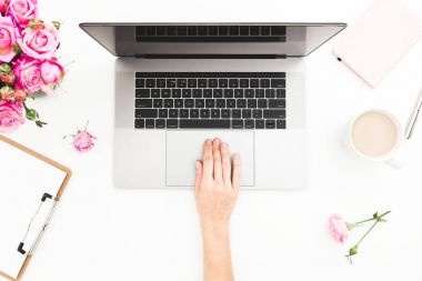 Dizüstü bilgisayarda çalışan kız. Kadın çalışma alanıyla eller, laptop, pembe gül buketi, kahve kupa, günlük Beyaz masada. Üstten Görünüm. Düz yatıyordu.