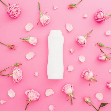 Gül yaprakları ve pembe bir arka plan üzerinde şampuan ile çerçeve çiçek. Güzellik kavramı. Düz yatıyordu, en iyi görünümü.