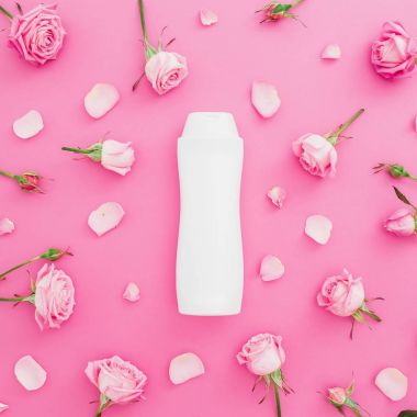 Gül yaprakları ve pembe bir arka plan üzerinde şampuan ile çerçeve çiçek. Güzellik kavramı. Düz yatıyordu, en iyi görünümü.