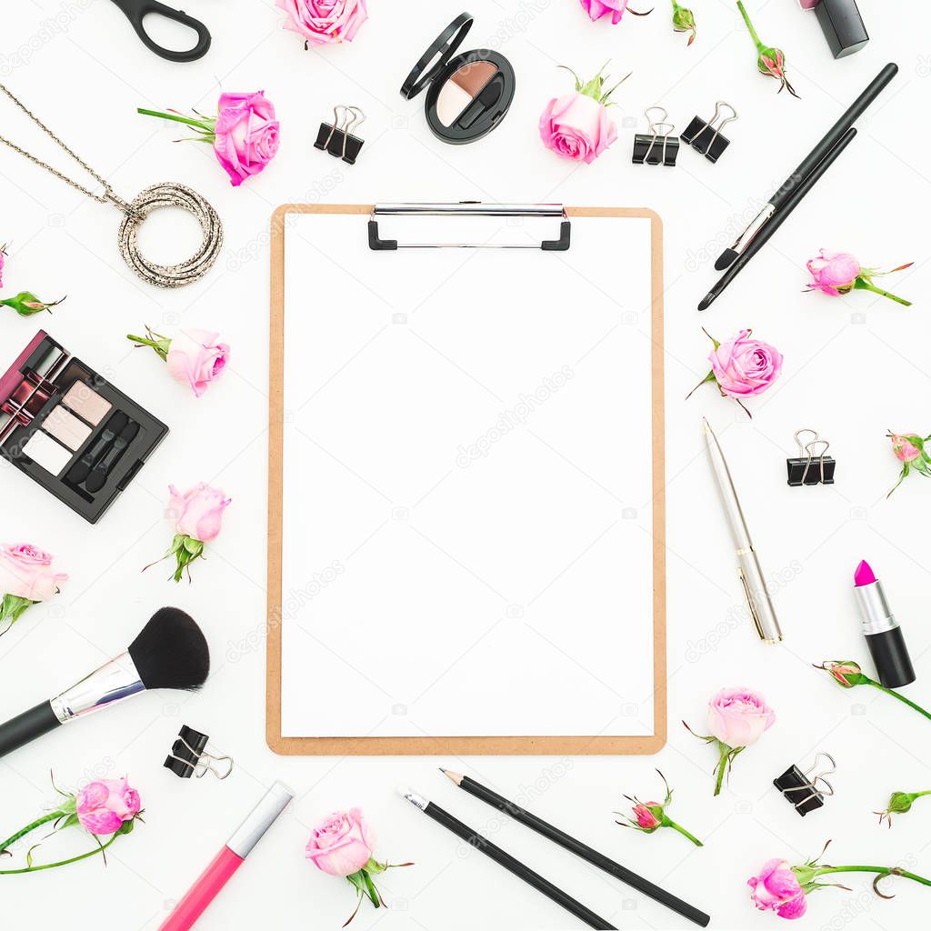 Woman workspace with cosmetics clipboard, accessories and pink roses on white background. Top view. Flat lay. Beauty blog background
