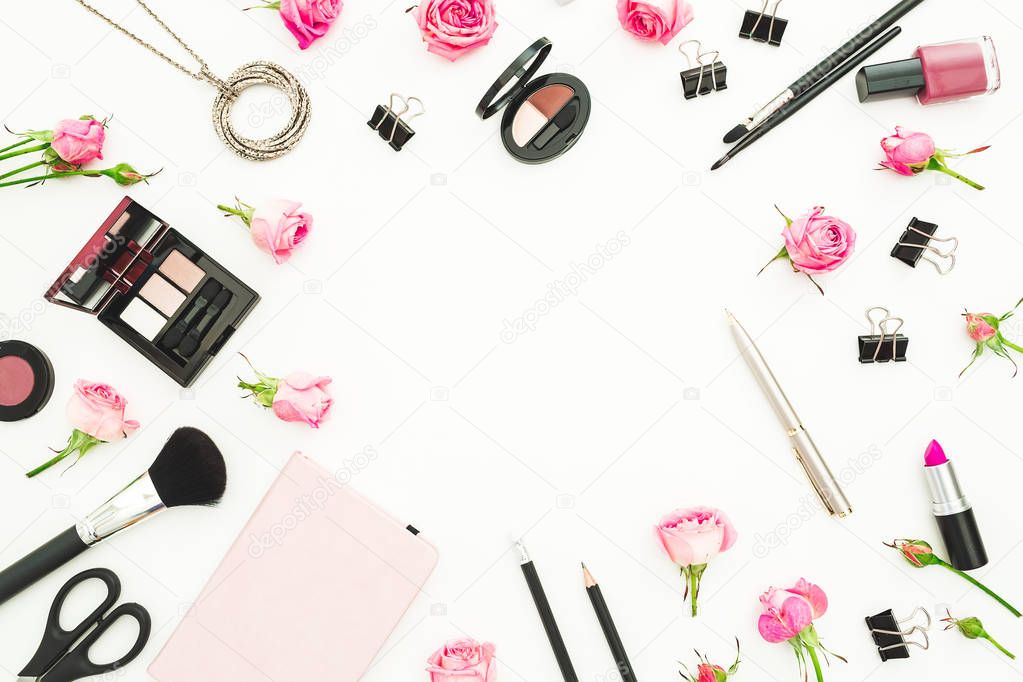 Female workspace with cosmetics, accessories and pink roses on white background. Top view. Flat lay. Beauty blog background