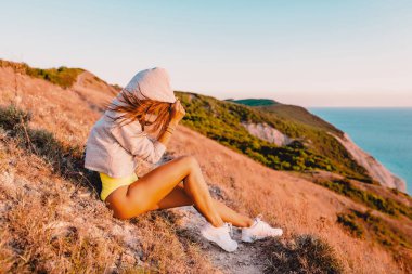 Genç kadın sıcak gün batımında doğada rahatlatıcı. Fitness kız dağlarda