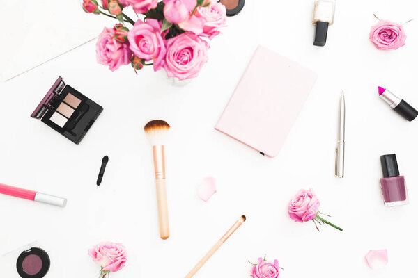 Woman workspace with pink roses, cosmetics, diary on white background. Top view. Flat lay. Valentines day.
