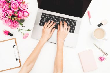 Dizüstü bilgisayarda çalışan kız. Office workspace eller, laptop, pembe gül buketi, kahve kupa, beyaz masa üzerinde günlüğü ile. Üstten Görünüm. Düz yatıyordu.