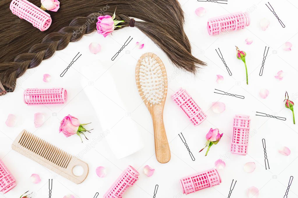 Frame with combs for hair styling, curlers, curlers and pink roses on white background. Beauty blog composition. Flat lay, top view
