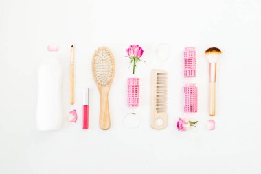 Çerçeve için curlers, styling saç tarak ile yapmak için fırçalar ve beyaz arka plan üzerinde pembe güller. Güzellik blog kompozisyon. Düz yatıyordu, en iyi görünümü