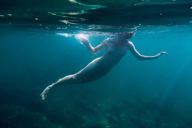 Su altında mavi okyanusta yüzmeye çıplak genç kadın