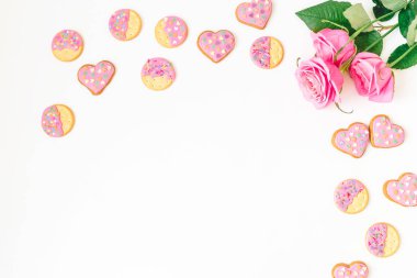 Pembe sır ve beyaz zemin üzerine gül ile tatlılar. Kompozisyon seviyorum. Düz yatıyordu. Üstten Görünüm.