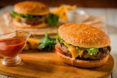 Burger lezzetli sığır eti, salata, sos ve domates koyu arka plan üzerinde. Amerikan Mutfagi