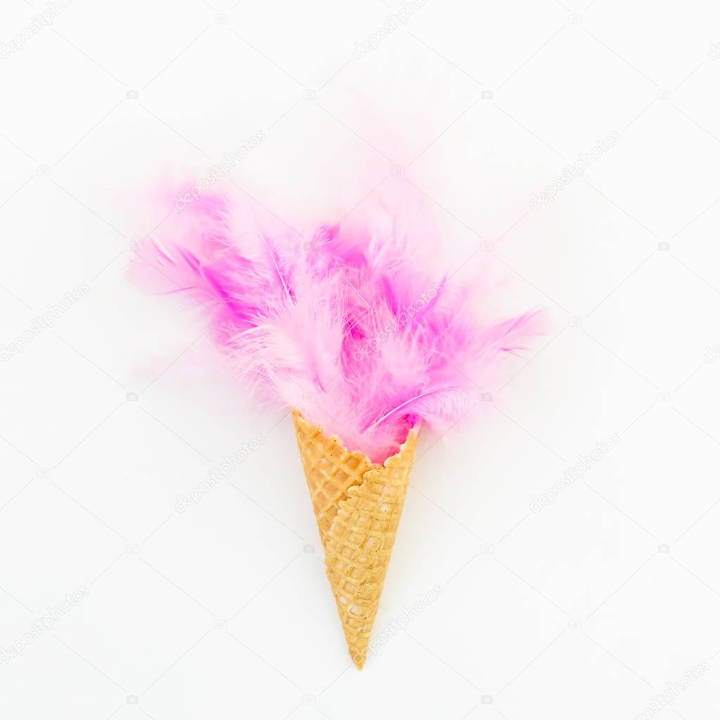 Pink feather in waffle cone on white background. Flat lay. Top view. Creative concept.