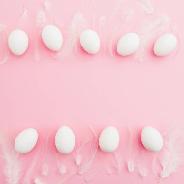 Paskalya yumurtaları ve pembe bir arka plan beyaz tüyler. Düz yatıyordu. Üstten Görünüm