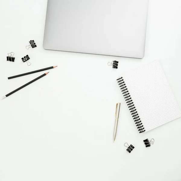 Top view of closed laptop with pen, pencils and notebook on white background