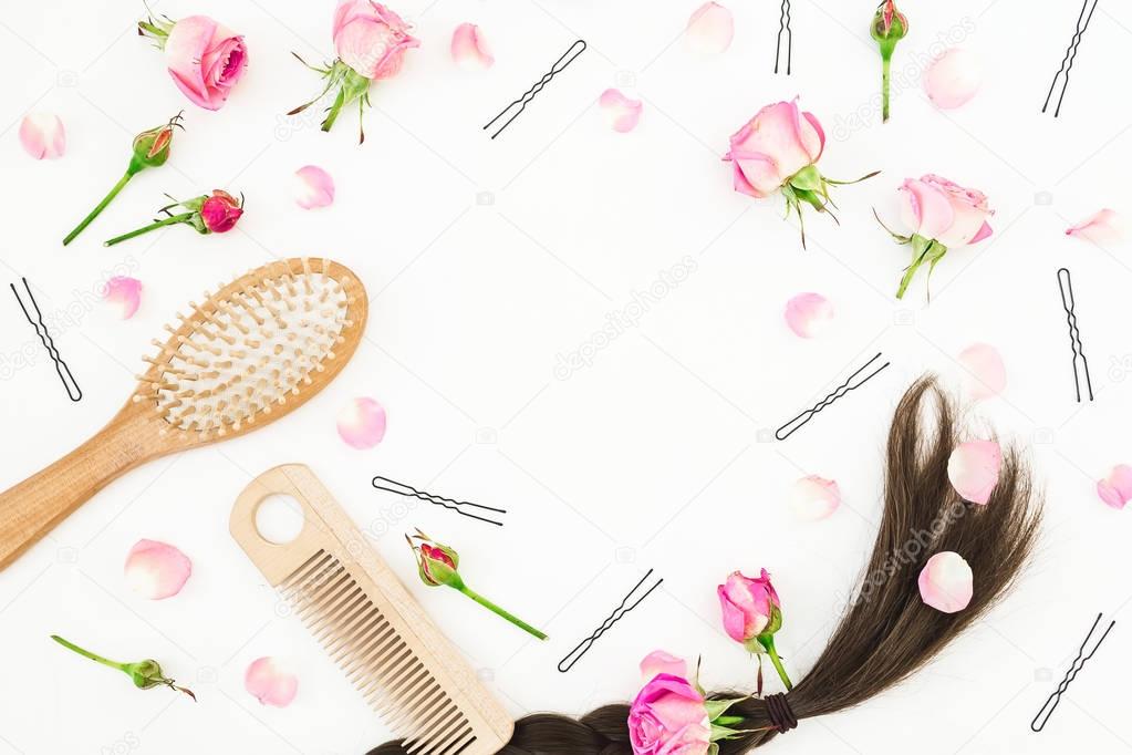 Frame with combs for hair styling, pink roses and hairpins on white background. Beauty blog composition. Flat lay, top view