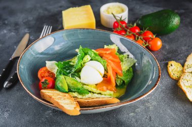 Sezar salatası yumurta, somon, avokado, kiraz domates ve gri arka plan üzerinde ızgara tost