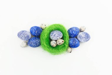 Mavi benekli Paskalya yumurta beyaz zemin üzerine yeşil yuvaya. Düz yatıyordu. Üstten Görünüm