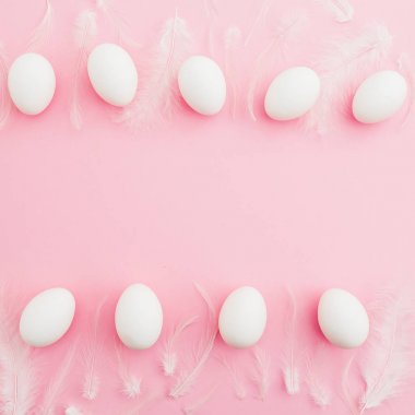 Paskalya yumurtaları ve pembe bir arka plan beyaz tüyler. Düz yatıyordu. Üstten Görünüm