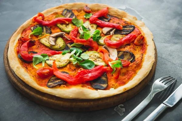 Vegetarian pizza with peppers, tomatoes, zucchini on dark background. Flat lay, top view. Food background