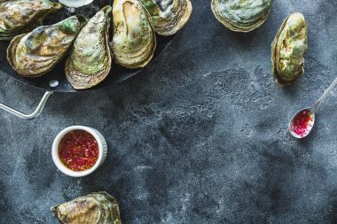 Taze istiridye tabağı sos ve koyu arka plan üzerinde kopya alanı ile buz ile. Düz yatıyordu. Üstten Görünüm