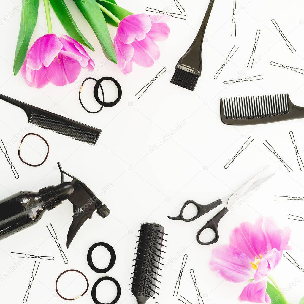 Top view of hairdressing tools with pink tulips on white background