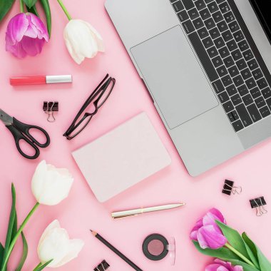 Ofis büro dizüstü bilgisayar, Beyaz Lale, gözlük, kalem ve pembe bir arka plan için makaslar. Düz yatıyordu. Üstten Görünüm. Kopya alanı ile serbest meslek kompozisyon.