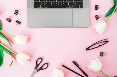 Ofis büro dizüstü bilgisayar, Beyaz Lale, gözlük, kalem ve pembe bir arka plan için makaslar. Düz yatıyordu. Üstten Görünüm. Kopya alanı ile serbest meslek kompozisyon.