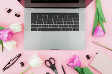 Ofis büro dizüstü bilgisayar, Beyaz Lale, gözlük, kalem ve pembe bir arka plan için makaslar. Düz yatıyordu. Üstten Görünüm. Kopya alanı ile serbest meslek kompozisyon.