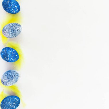 Mavi benekli Paskalya yumurtaları ve beyaz zemin üzerine sarı tüyler. Düz yatıyordu. Üstten Görünüm