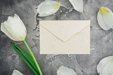 gri taş zemin üzerine Beyaz Lale ile beyaz zarf