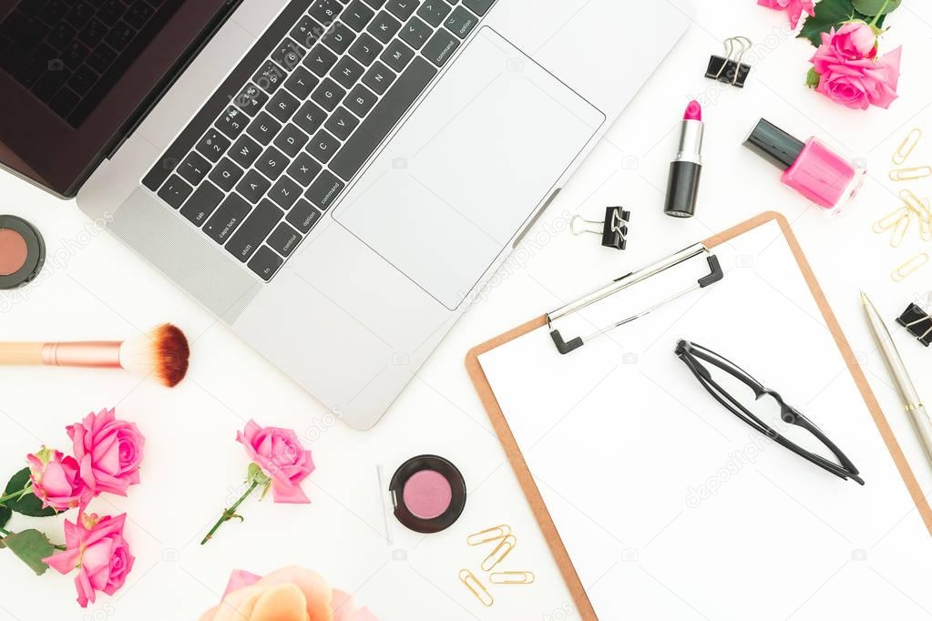 Laptop, clipboard, roses flowers, cosmetics and accessories on white background. Flat lay. Top view. Freelancer office concept