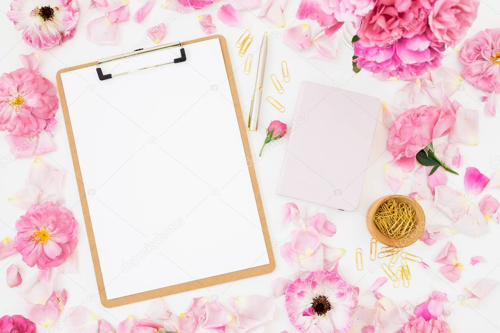 Beauty blog composition with dairy, pink roses, petals and clipboard on white background. Top view. Flat lay.