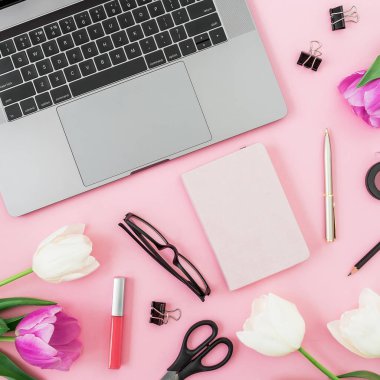 Dizüstü bilgisayar, gözlük ve ofis aletleri ile güzel Lale çiçek pembe bir arka plan üzerinde yukarıdan